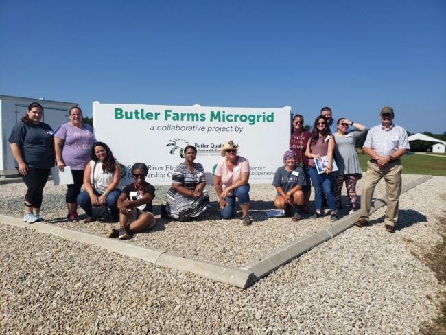 Teachers posing for a photo outdoors in front of a sign.