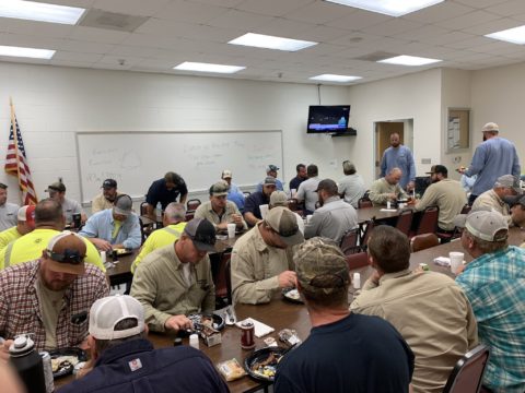 Crews in a room, eating and getting ready to work