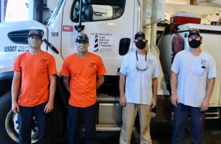 Lineworkers standing in front of truck